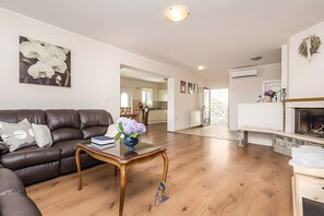 A living room with a leather sofa, a wooden coffee table, and a fireplace. - Charming 5-BR Villa with Pool near Beaches (Lovran)