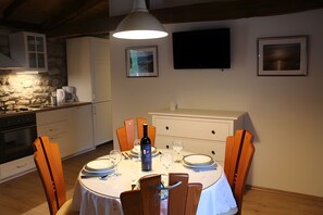 Ein Essbereich mit einem runden Tisch für zwei Personen, einem weißen Schrank und einem an der Wand befestigten Fernseher.