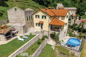 Una villa con una torre de piedra, una piscina y un jardín bien cuidado.