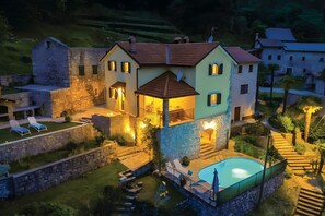 Ein zweistöckiges Haus mit Swimmingpool, Steinmauern und einer Terrasse.
