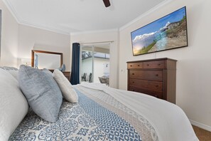 Un dormitorio con cama, cómoda, espejo y un cuadro de un paisaje montañoso.