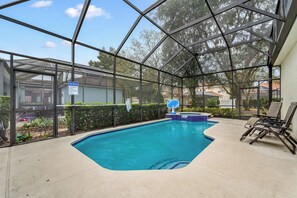 Una piscina interior con paredes de vidrio transparente, borde de azulejos azules y un letrero con las normas de la piscina.
