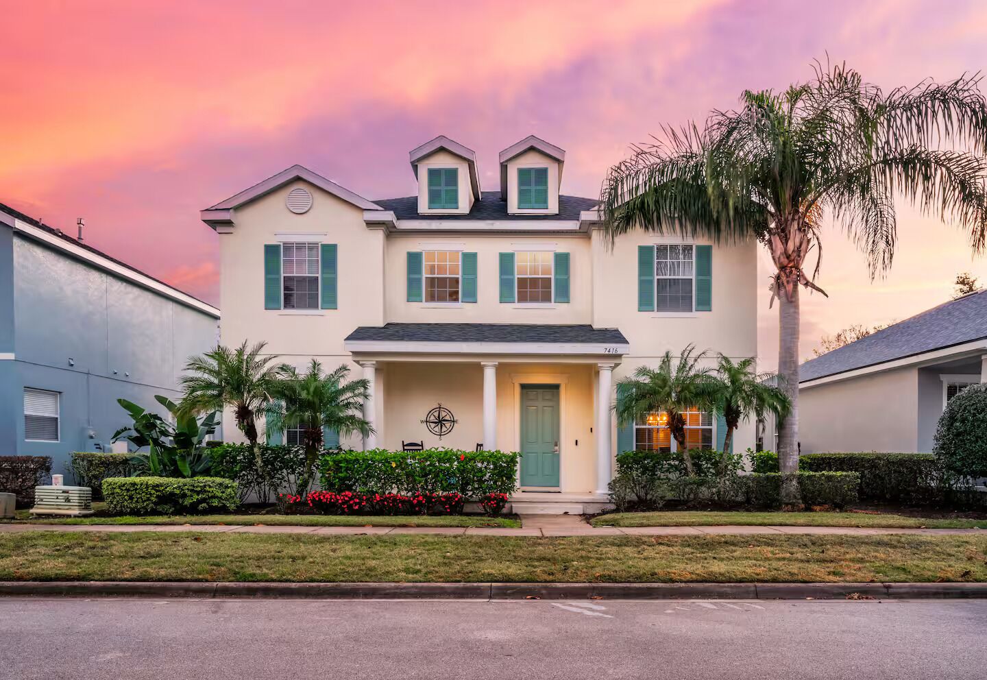 A two-story house with a front porch, a compass sign, and a palm tree.