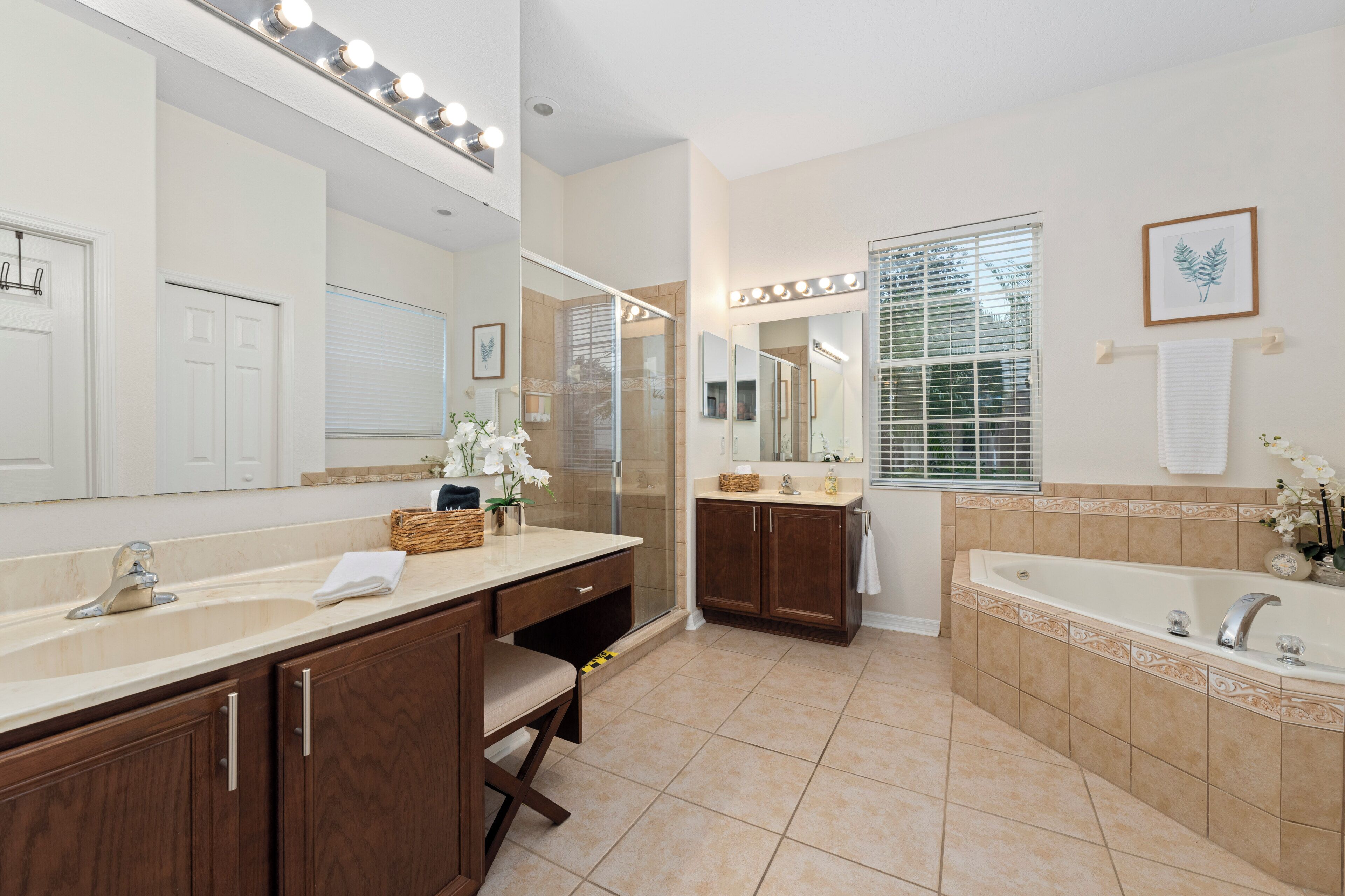 A bathroom with a vanity, a bathtub, and a large mirror with lights.