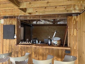 Ein Holzinterieur mit Barbereich, Barhocker und einer Spirituosenflasche.
