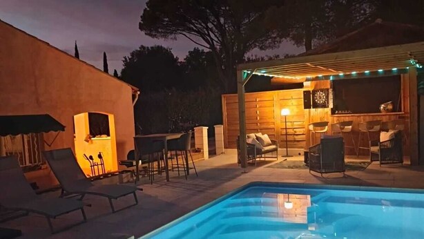 En swimmingpool med liggestole og et grillområde.