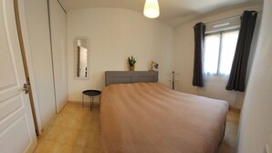A bedroom with a bed, a bedside table, a mirror, a window with curtains, and a ceiling light. - 🌿Cozy Two-Bedroom Apartment in Aix-en-Provence (2 people)🌿 (Aix-en-Provence)