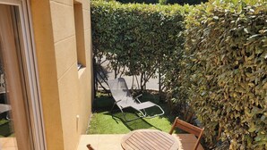 A patio with a table and chairs, a hedge, and a lawn chair in the background. - 🌿Cozy Two-Bedroom Apartment in Aix-en-Provence (2 people)🌿 (Aix-en-Provence)
