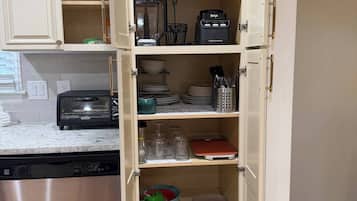 A kitchen with a built-in cabinet, a coffee maker, a toaster, and a dish rack.