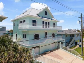 Ein zweistöckiges Haus mit Balkon, Garage und Treppe zum Obergeschoss.