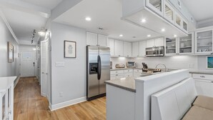 A modern kitchen with white cabinetry, stainless steel appliances, and a central island. - Marker 33 #1c3 (New Smyrna Beach)