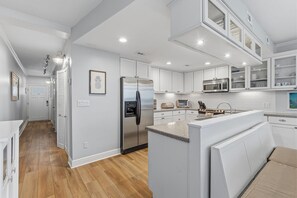 A modern kitchen with white cabinetry, stainless steel appliances, and a central island. - Marker 33 #1c3 (New Smyrna Beach)