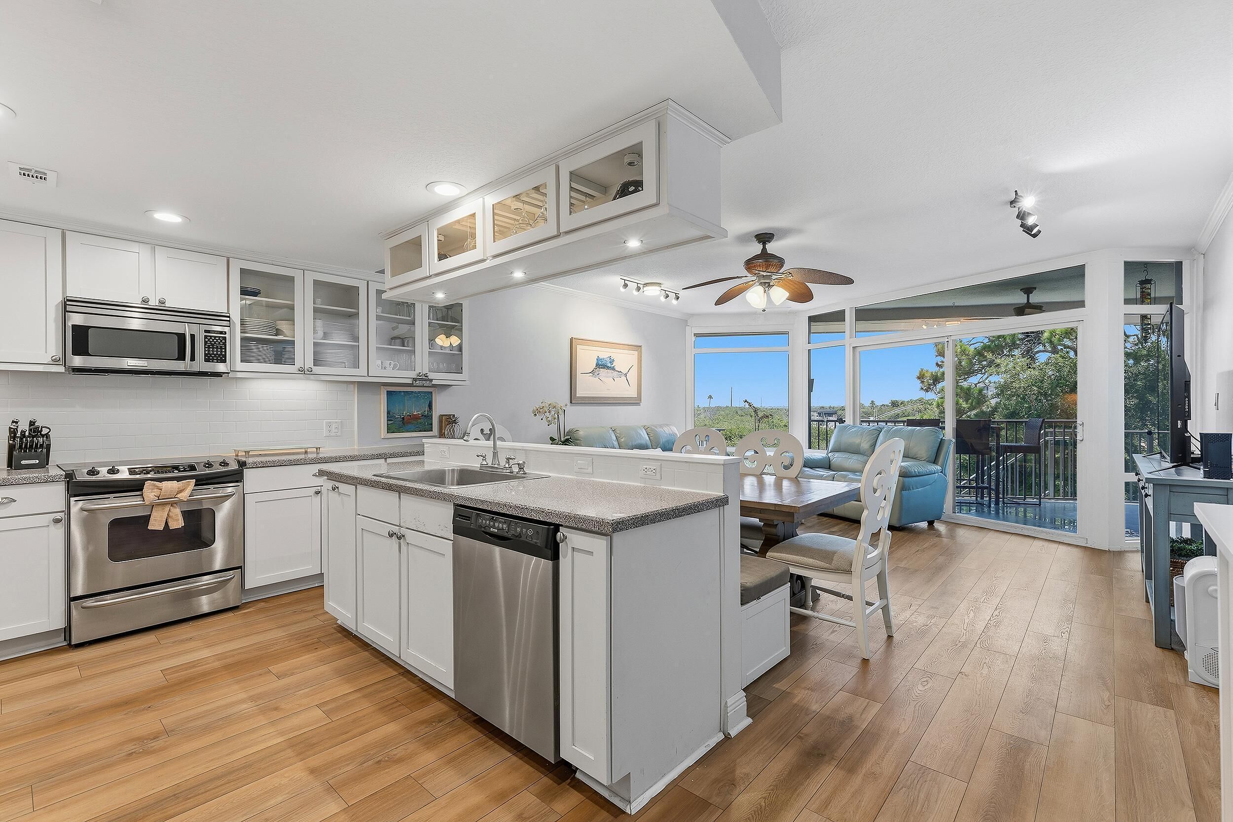 A modern kitchen with a central island, built-in appliances, and a dining area with a view.