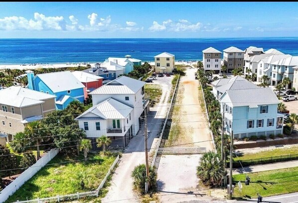 Uma área residencial à beira-mar, com casas, praia e céu claro.