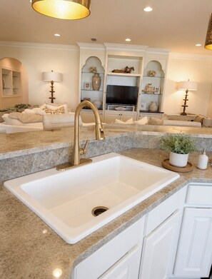 A modern kitchen with a central white sink, granite countertops, and white cabinetry. -     BleuSalt No. 16 Luxury Beach Retreat in The  Villages of Tannin (Orange Beach)