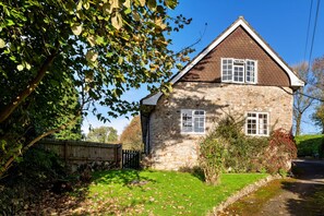 A stone house with a pitched roof, two windows, and a wooden gate. - Coastal Family House for 8 in Cornwall (Axminster)