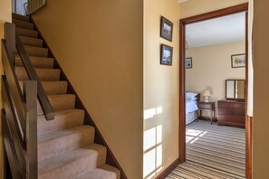 A carpeted staircase leading to a bedroom with a bed, bedside table, and dresser. - Modern Plymouth Apartment Near The Hoe (Ilfracombe)