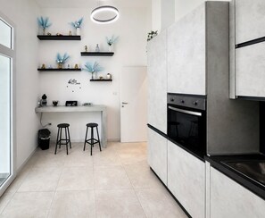 Eine moderne Küche mit Backofen, einer Kaffeestation und zwei Barhocker.