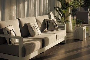 Ein modernes Wohnzimmer mit einer Couch, Kissen, einem Beistelltisch und einer Topfpflanze.