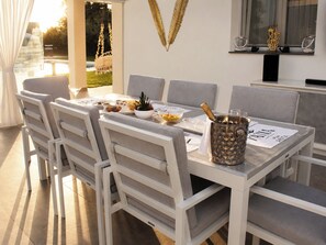 A dining area with a table set for two, a champagne bottle, and a decorative wall piece. - Natia Sicily Villa Anita (Sicilia)