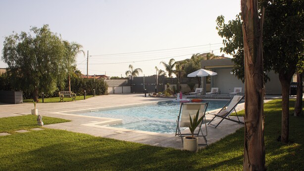 A swimming pool with lounge chairs and a small garden area. - Natia Sicily Villa Anita (Sicilia)