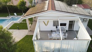 A modern house with a covered patio, a pool, and a well-maintained lawn. - Natia Sicily Villa Anita (Sicilia)