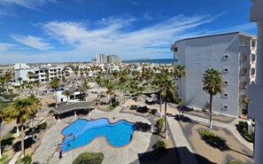 A resort with a swimming pool, palm trees, and a view of the sea. - Pets love sandy beach at casa blanca (Puerto Peñasco)