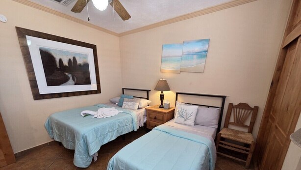 A bedroom with two beds, a nightstand, a chair, and artwork on the walls. - Pets love sandy beach at casa blanca (Puerto Peñasco)