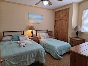 A bedroom with two beds, wooden wardrobe, and a ceiling fan. - Pets love sandy beach at casa blanca (Puerto Peñasco)