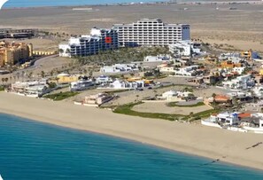 Ein Küstenhotel mit mehreren Gebäuden, einem Strand und einem Steg.