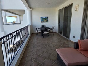 A balcony with a dining table and chairs, a sofa, and a painting on the wall. - Pets love sandy beach at casa blanca (Puerto Peñasco)