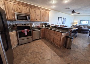 A kitchen with wooden cabinets, stainless steel appliances, and a tiled floor. - Pets love sandy beach at casa blanca (Puerto Peñasco)
