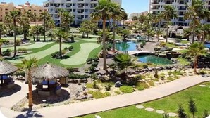 A resort with multiple-story buildings, a golf course, and a swimming pool area. - Pets love sandy beach at casa blanca (Puerto Peñasco)