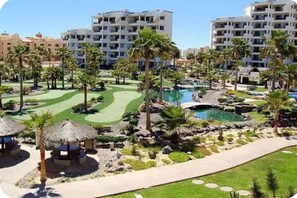 A resort with multiple-story buildings, a golf course, and a swimming pool area. - Pets love sandy beach at casa blanca (Puerto Peñasco)