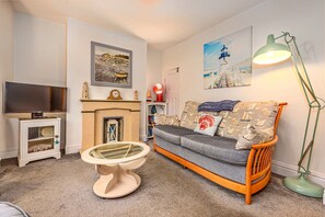 A living room with a sofa, a television, a fireplace, and artwork on the walls. - Welcoming Cottage Near Harbour (Whitby)