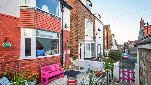 A narrow residential street with houses featuring red brick facades and white window frames. - Welcoming Cottage Near Harbour (Whitby)