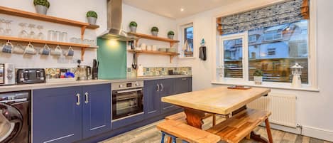 Uma cozinha moderna com armários azuis, uma mesa de madeira e uma janela com vista para uma paisagem nevada.