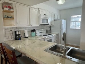 A kitchen with white cabinets, a microwave, a stove, a refrigerator, and a sink. - 3-Min Walk to Beach! King + 2 Queens, 2.5 Baths • Sleeps 6 (Fort Walton Beach)