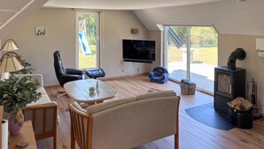A cozy living room with a flat-screen TV, a fireplace, and a dining area with a table and chairs. - 3 bedroom cozy home in Fur (Fur)