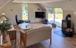A cozy living room with a flat-screen TV, a fireplace, and a dining area with a table and chairs. - 3 bedroom cozy home in Fur (Fur)