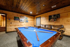 Ein Billardtisch in einem Raum mit Holzwänden und -decke.