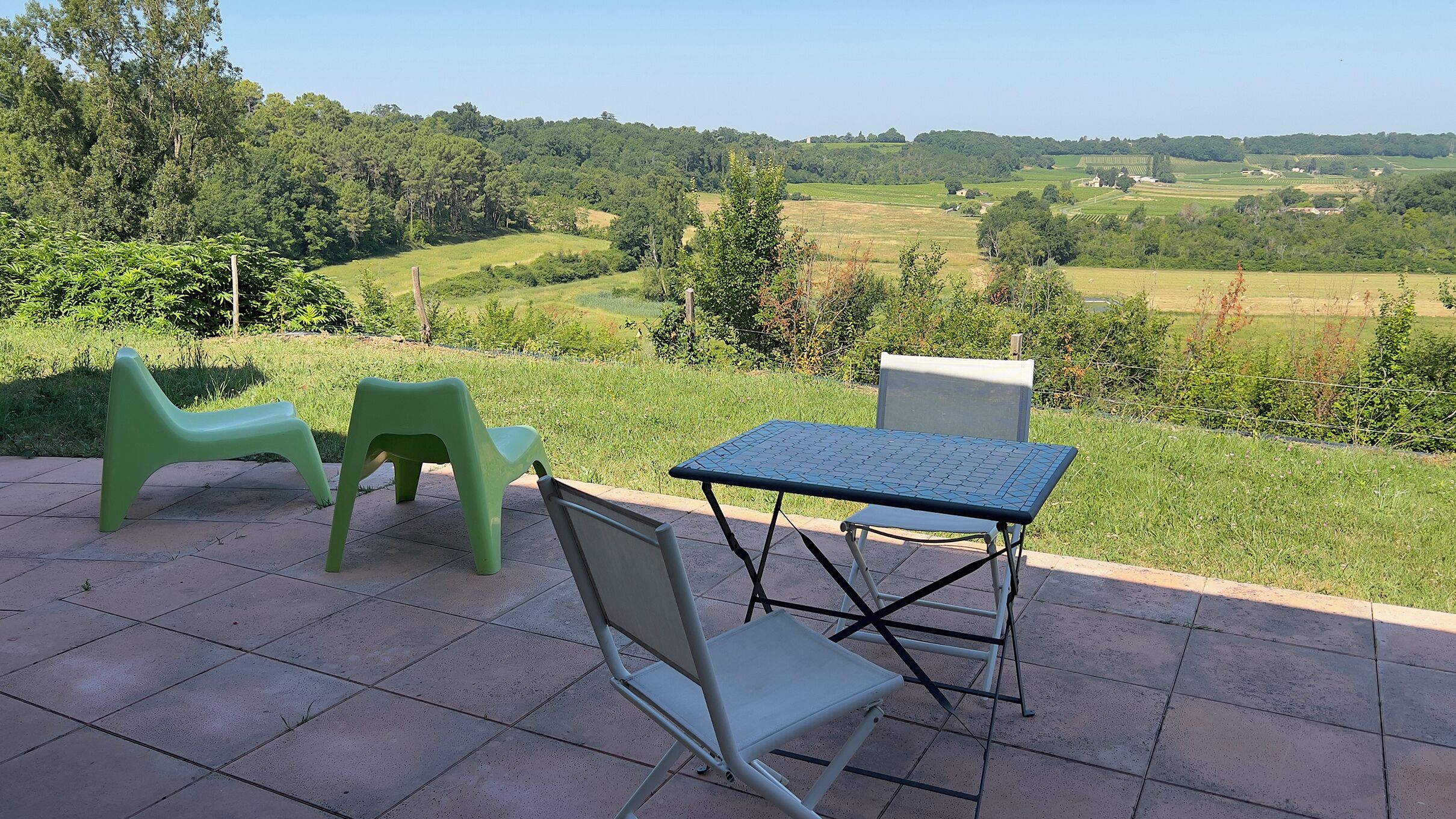 Un espacio al aire libre con mesa y sillas, con vista a un paisaje rural.
