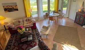 A living room with a sofa, a coffee table, a rug, and a dining area with chairs and a table.