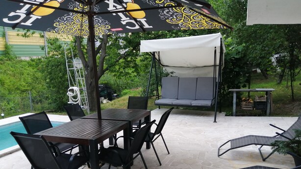 Eine Außenpatio mit Pool, Tisch und Stühlen, einer Schaukel und einem überdachten Sitzbereich.