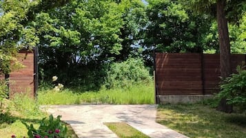 Caminho que serpenteia por um jardim com cerca de madeira e vegetação exuberante.