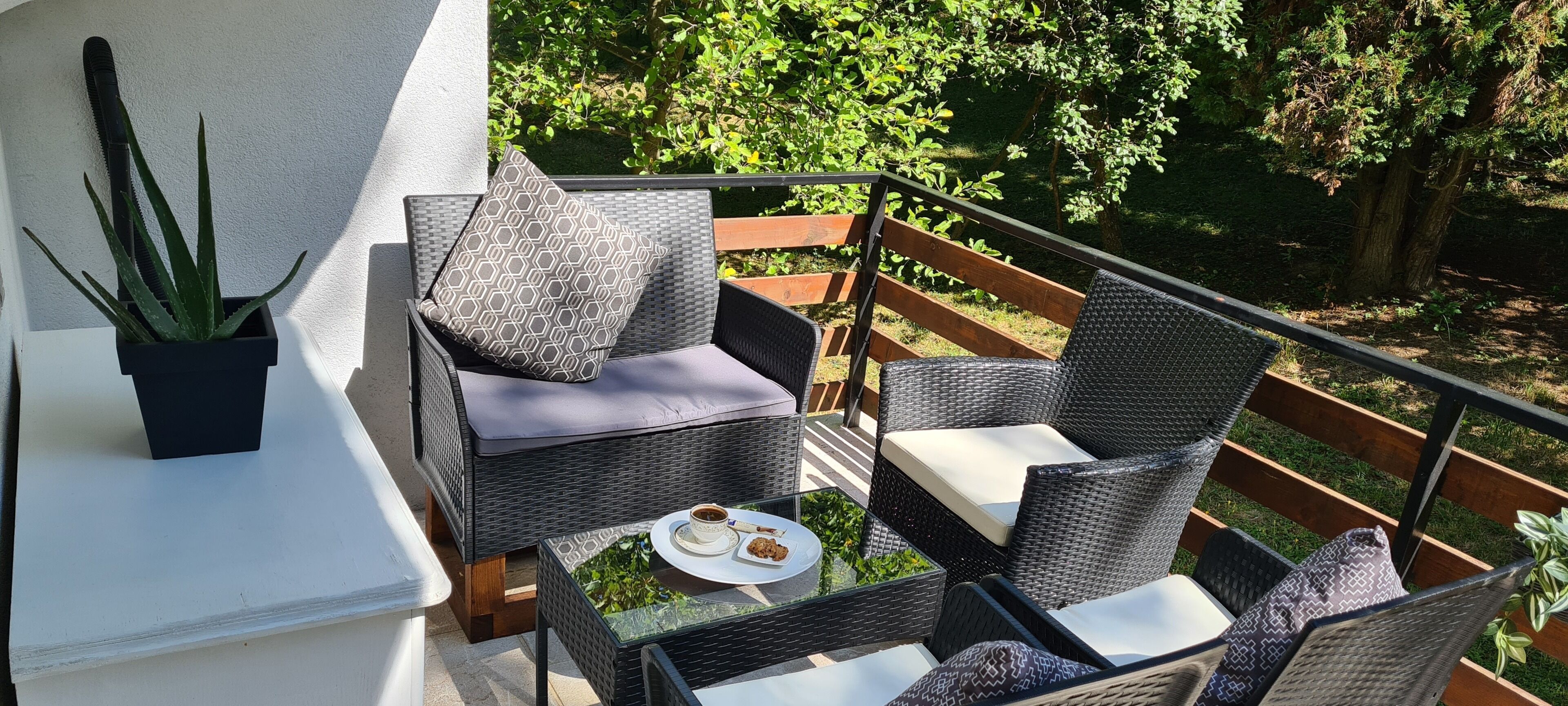 A balcony with wicker furniture, a small table, and a potted plant.