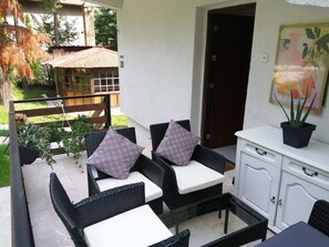 A patio area with wicker furniture, a white cabinet, and a potted plant.