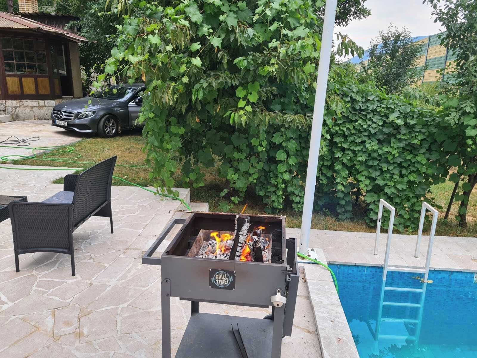 Um quintal com churrasqueira, móveis de pátio, piscina e um carro estacionado por perto.