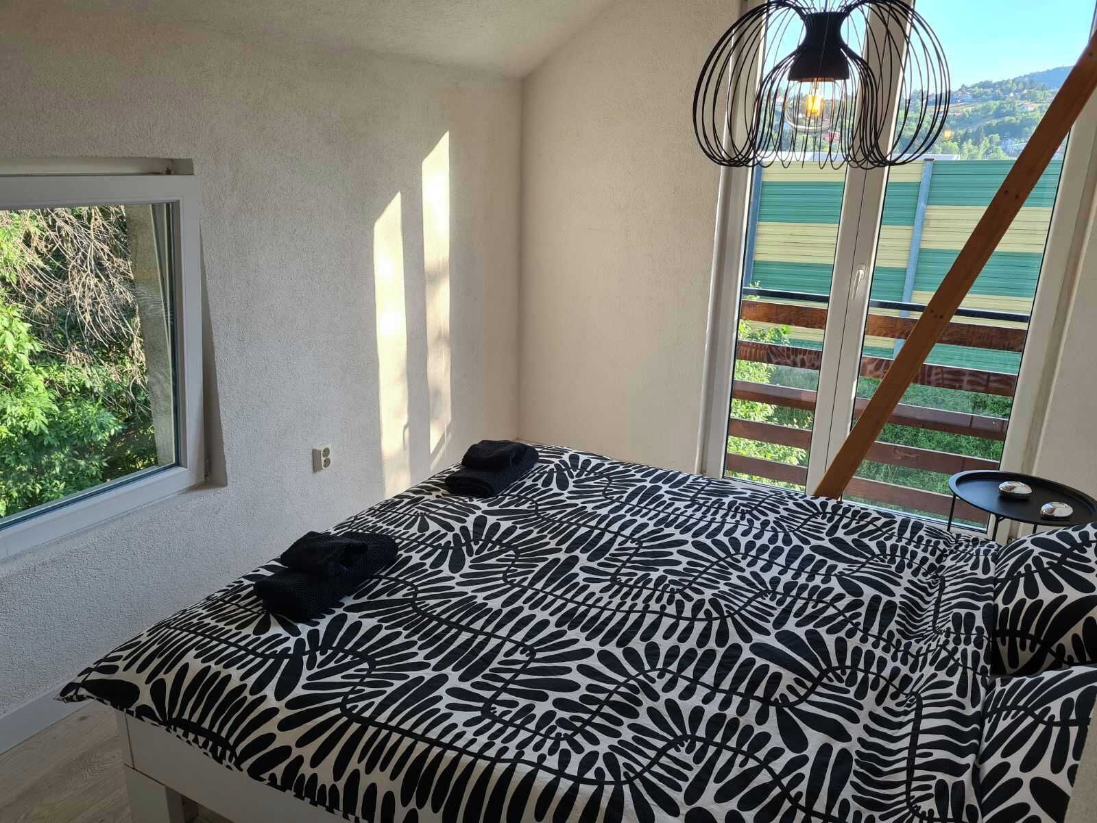 Quarto com cama, janela e vista para o verde.