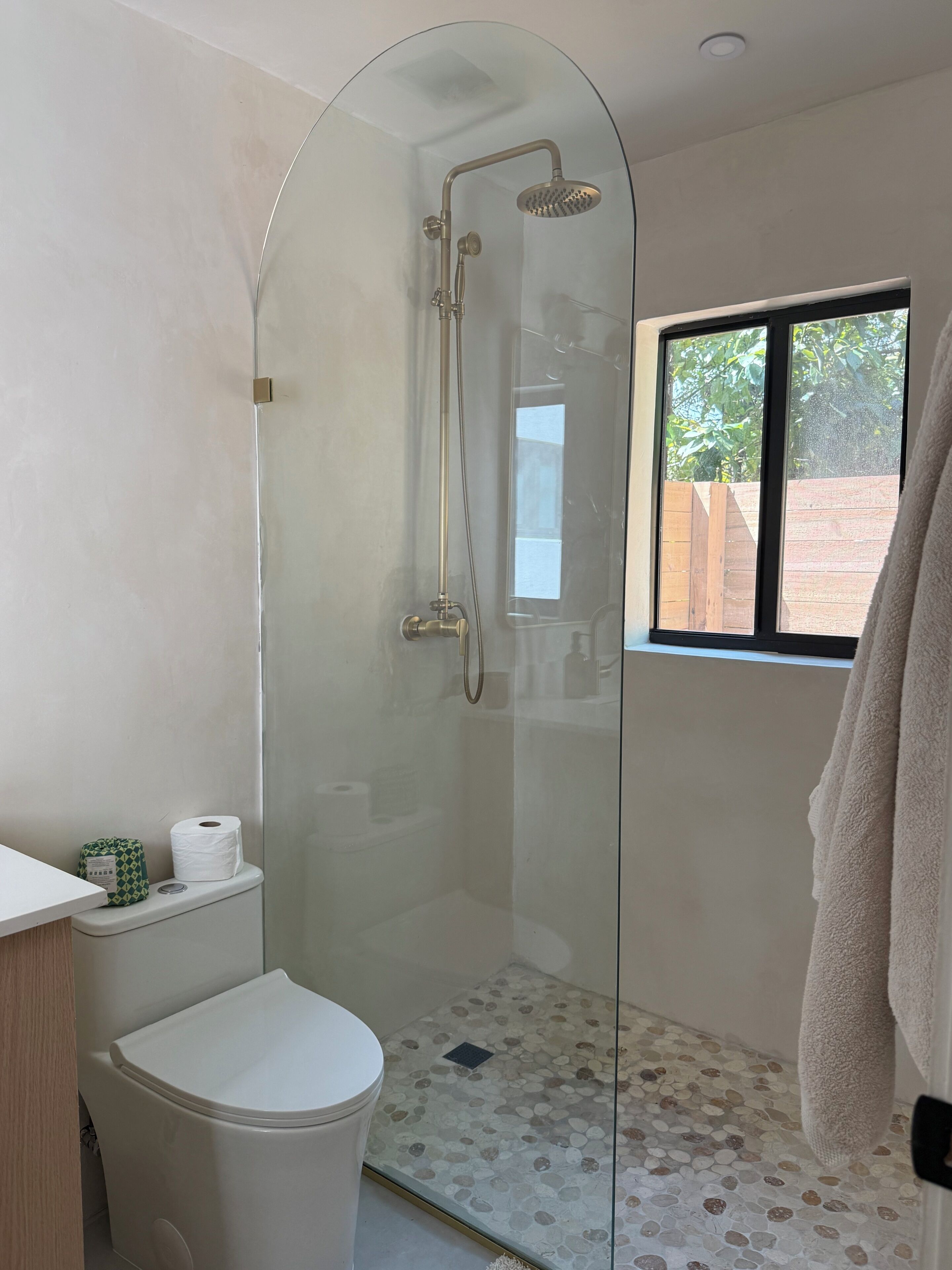 Ein Badezimmer mit Duschkabine, Toilette und Fenster.